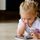 Ein kleines Mädchen liegt vor einem Smartphone und spielt damit