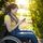Eine junge Frau mit Dreadlocks sitzt im Rollstuhl in einem Park und schaut auf ihr Smartphone