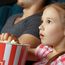 Ein Mädchen isst Popcorn und guckt gespannt einen Film