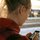Eine junge Frau steht an einem Bahnsteig und schaut auf ihr Handy. 