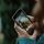 Eine Person hält ein Smartphone mit beiden Händen, auf dem die App "Snapchat" geöffnet ist. Durch die Kamerafunktion auf dem Bildschirm ist zu sehen, dass die Person eine Naturlandschaft filmt. 