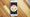 weißes iPhone liegt auf einem Holztisch mit einem großen wütenden Smiley auf dem Bildschirm.
