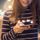 Eine Junge Frau hält ein Smartphone mit Hinweisen für neue Nachrichten