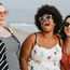 Drei Frauen stehen lachend am Strand