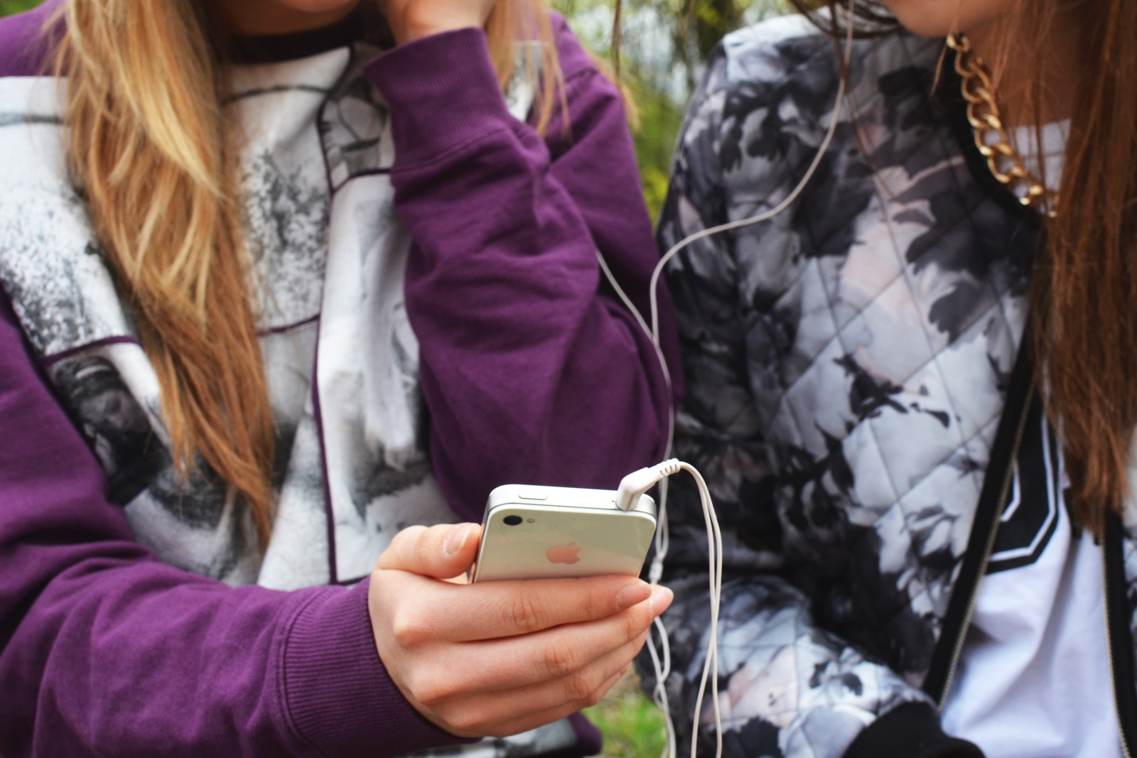 Zwei Teens mit Smartphone hoeren gemeinsam Musik mit Kopfhoerern