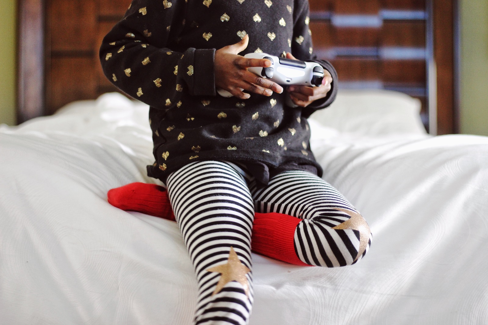 Ein Kind sitzt auf dem Bett mit einem Controller in der Hand