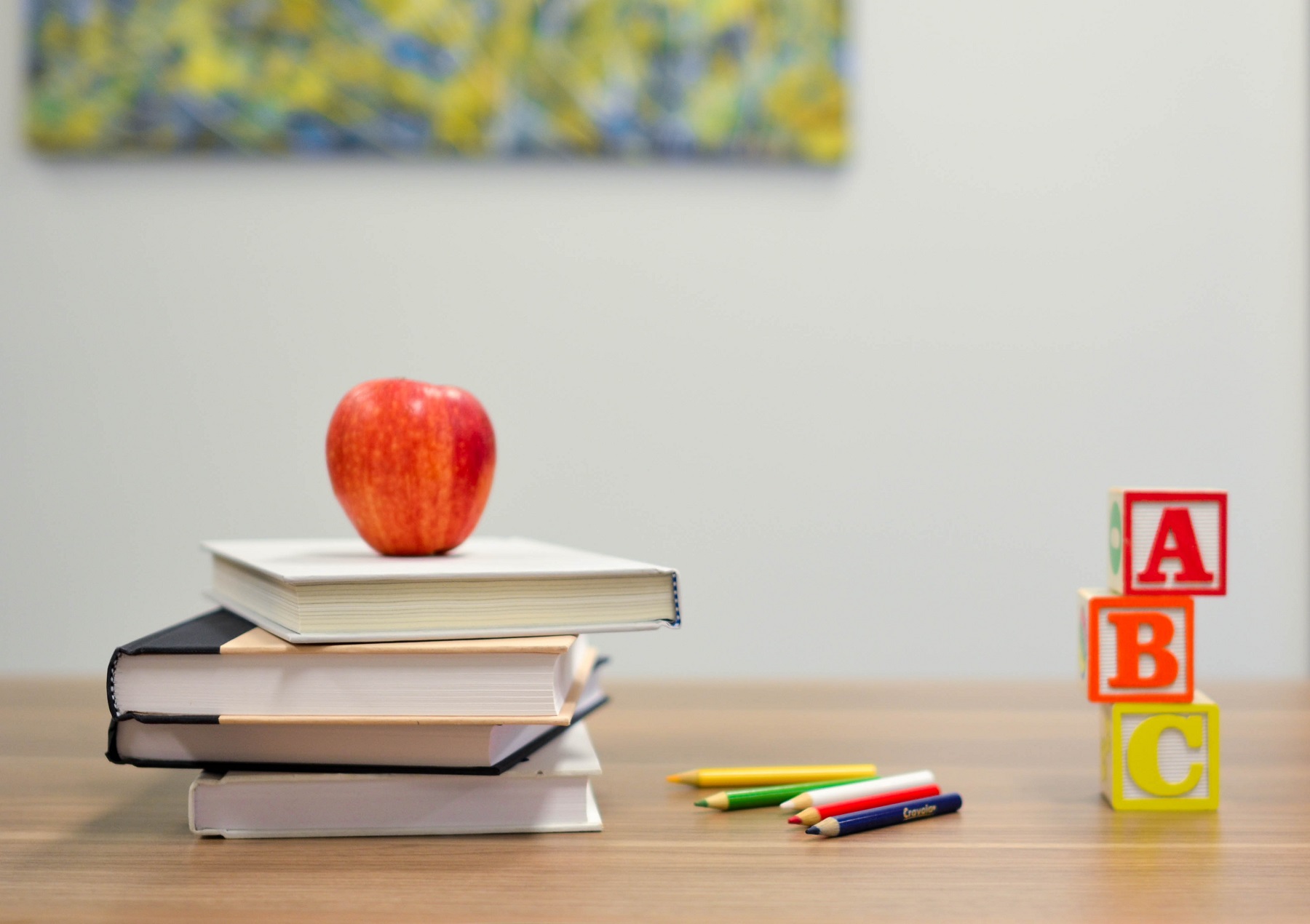 Ein Stapel Bücher mit Apfel, Stiften und Klötzchen