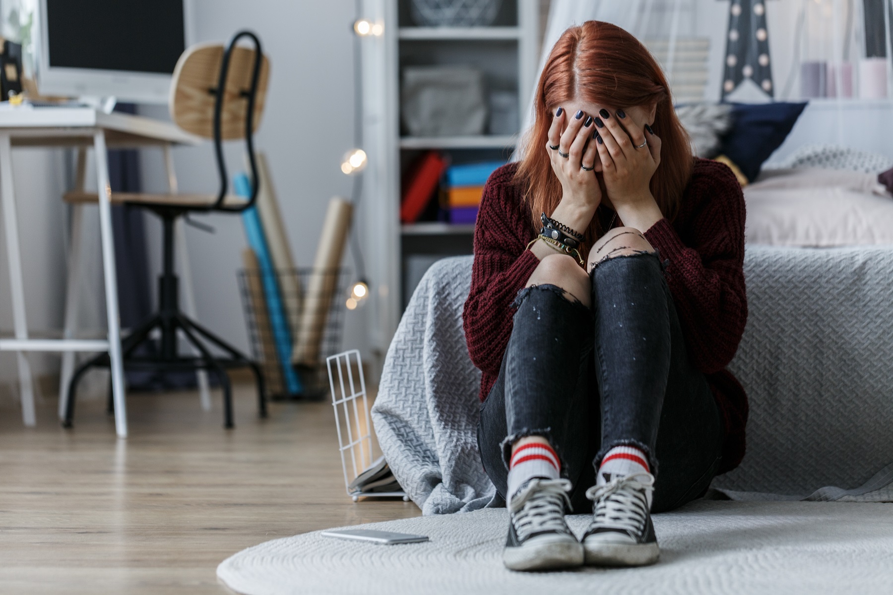 Eine Junge Frau sitzt auf dem Boden und Hand das Gesicht in den Händen