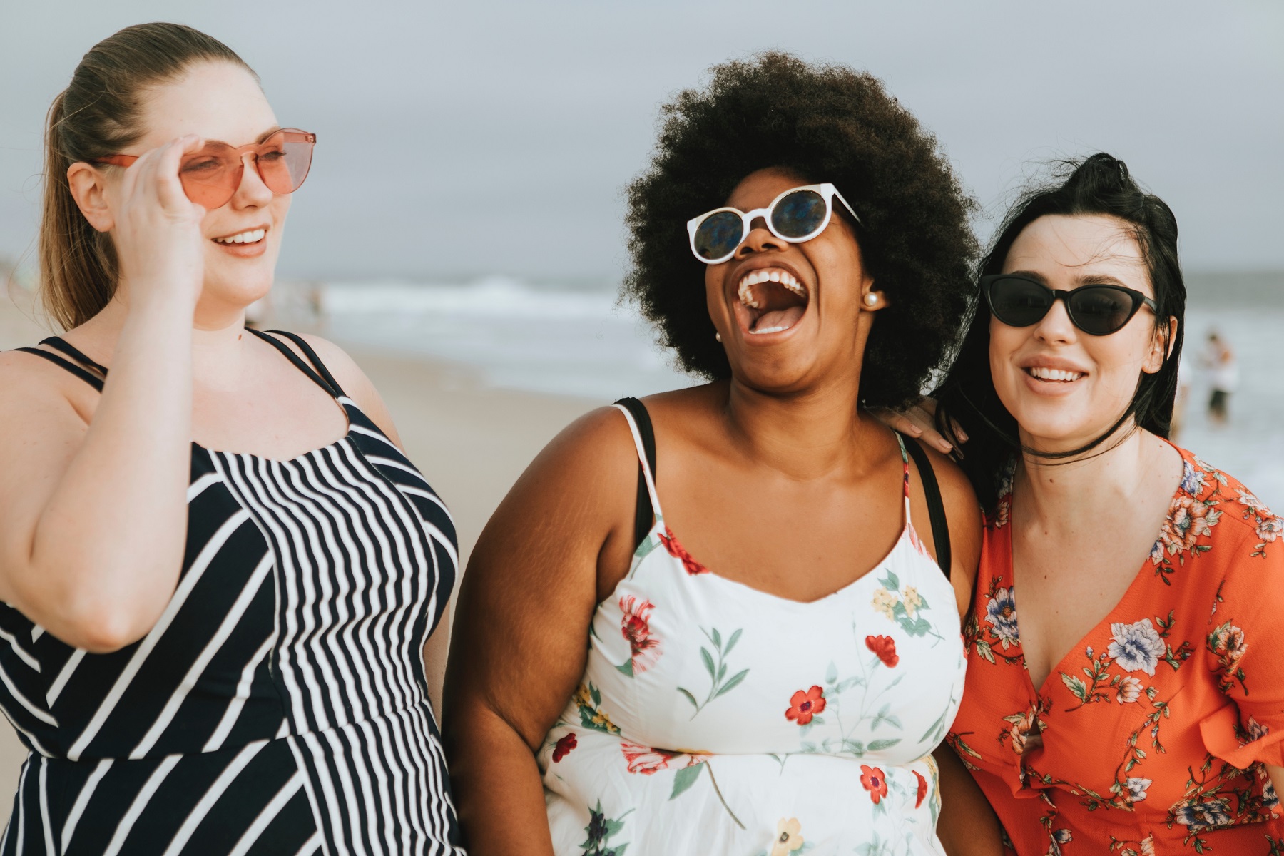 Drei Frauen stehen lachend am Strand