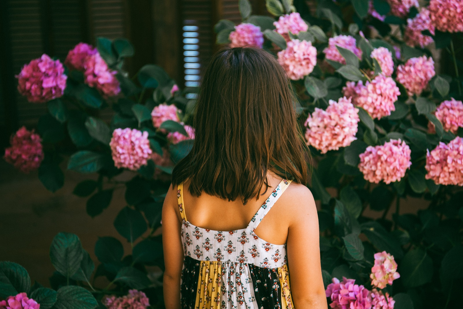 Ein Maedchen steht vor Blumen