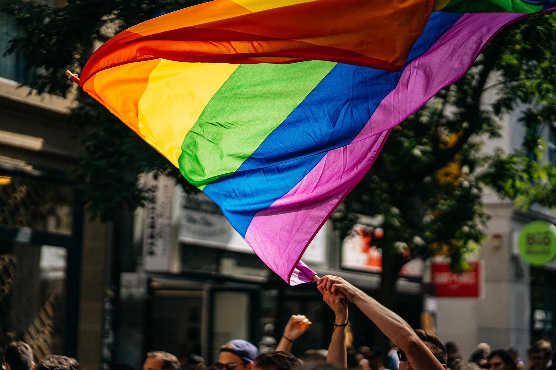 Eine Person schwenkt eine große Fahne in Regenbogenfahnen.