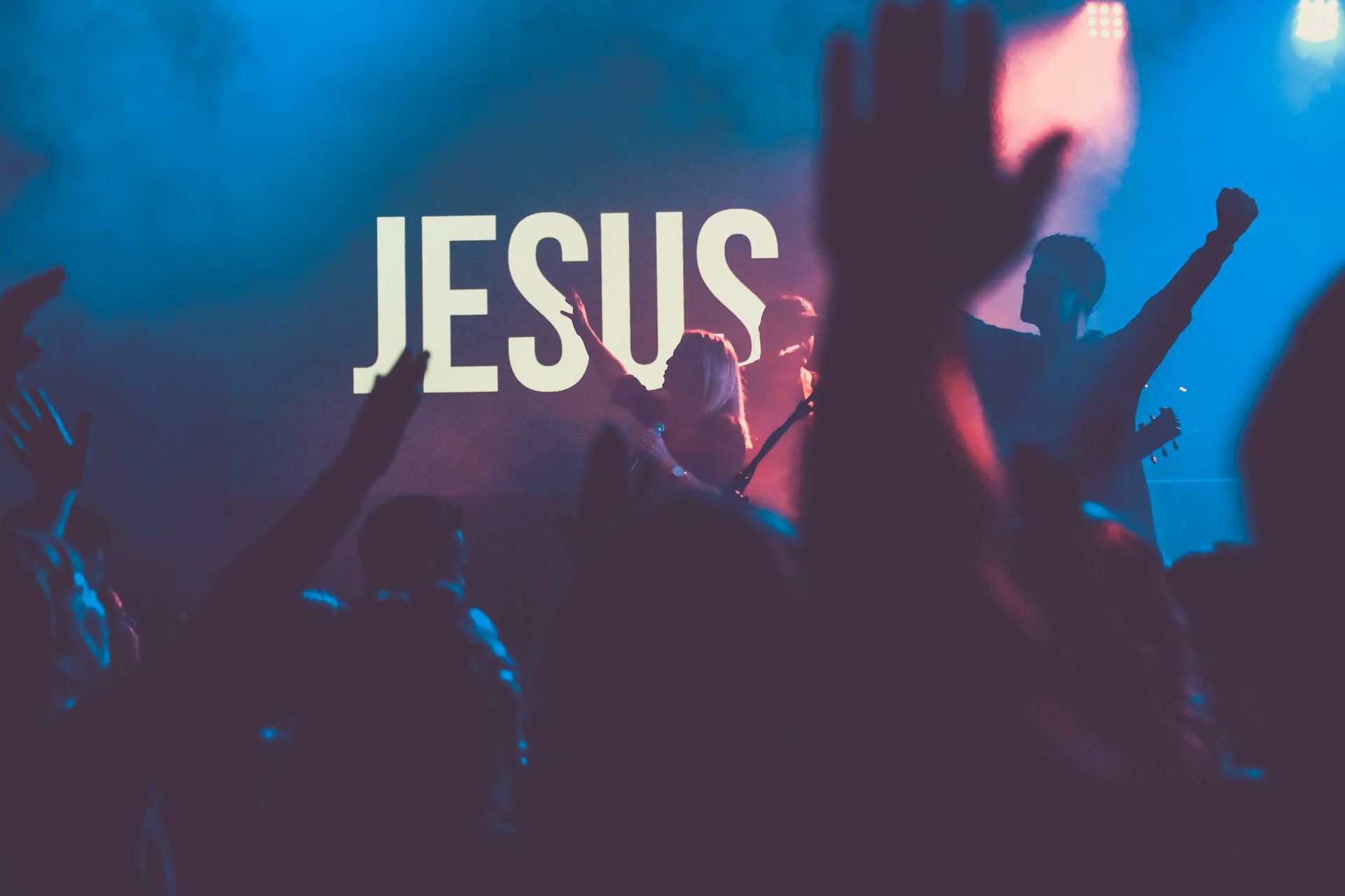 Menschen feiern vor einer Bühne. Auf der Bühne eine große Leinwand mit der Aufschrift "Jesus".