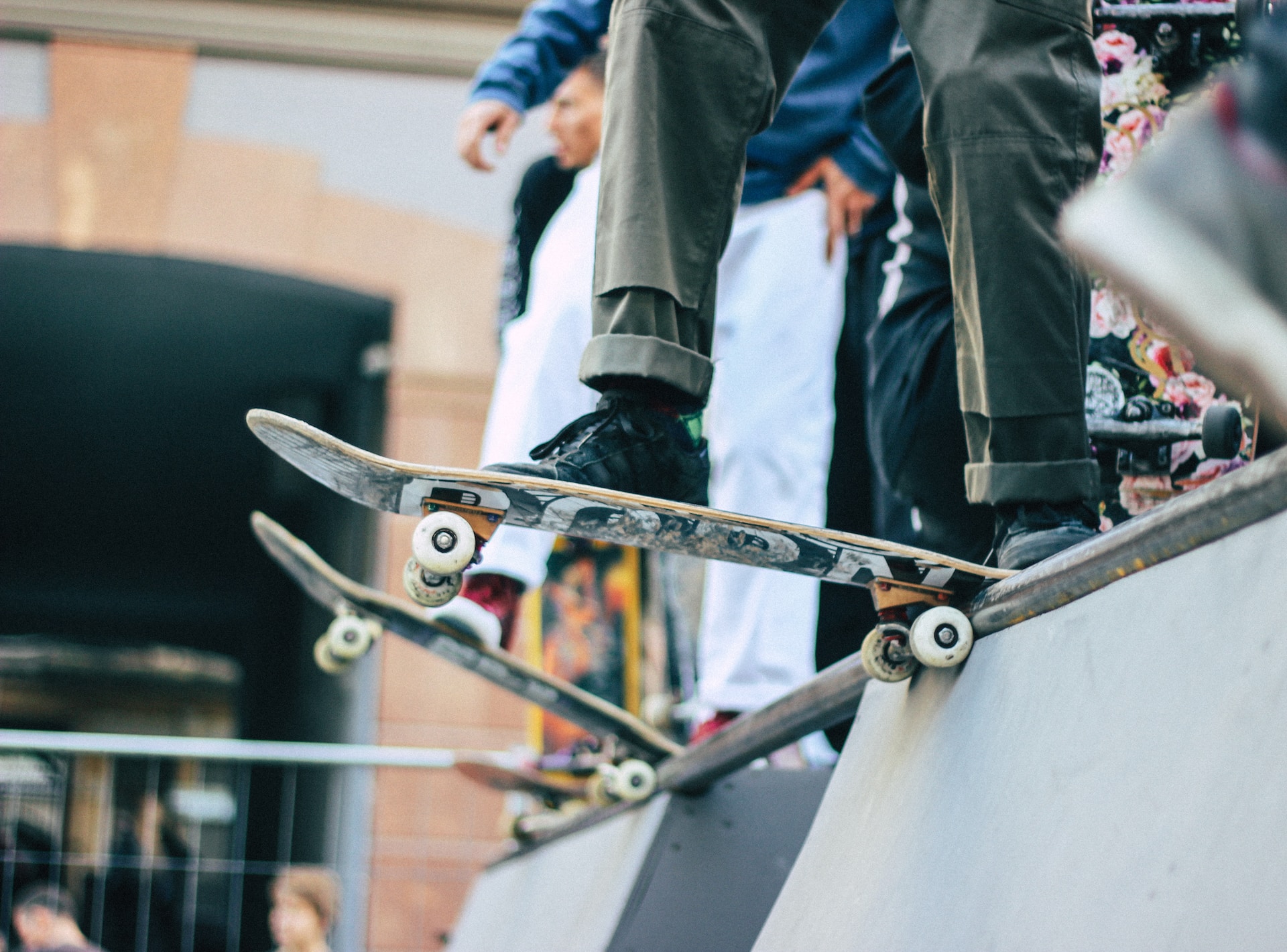 In einem Skatepark stehen mehrere Skater auf ihren Skateboards auf einer Rampe. Sie sind kurz vor der Abfahrt.
