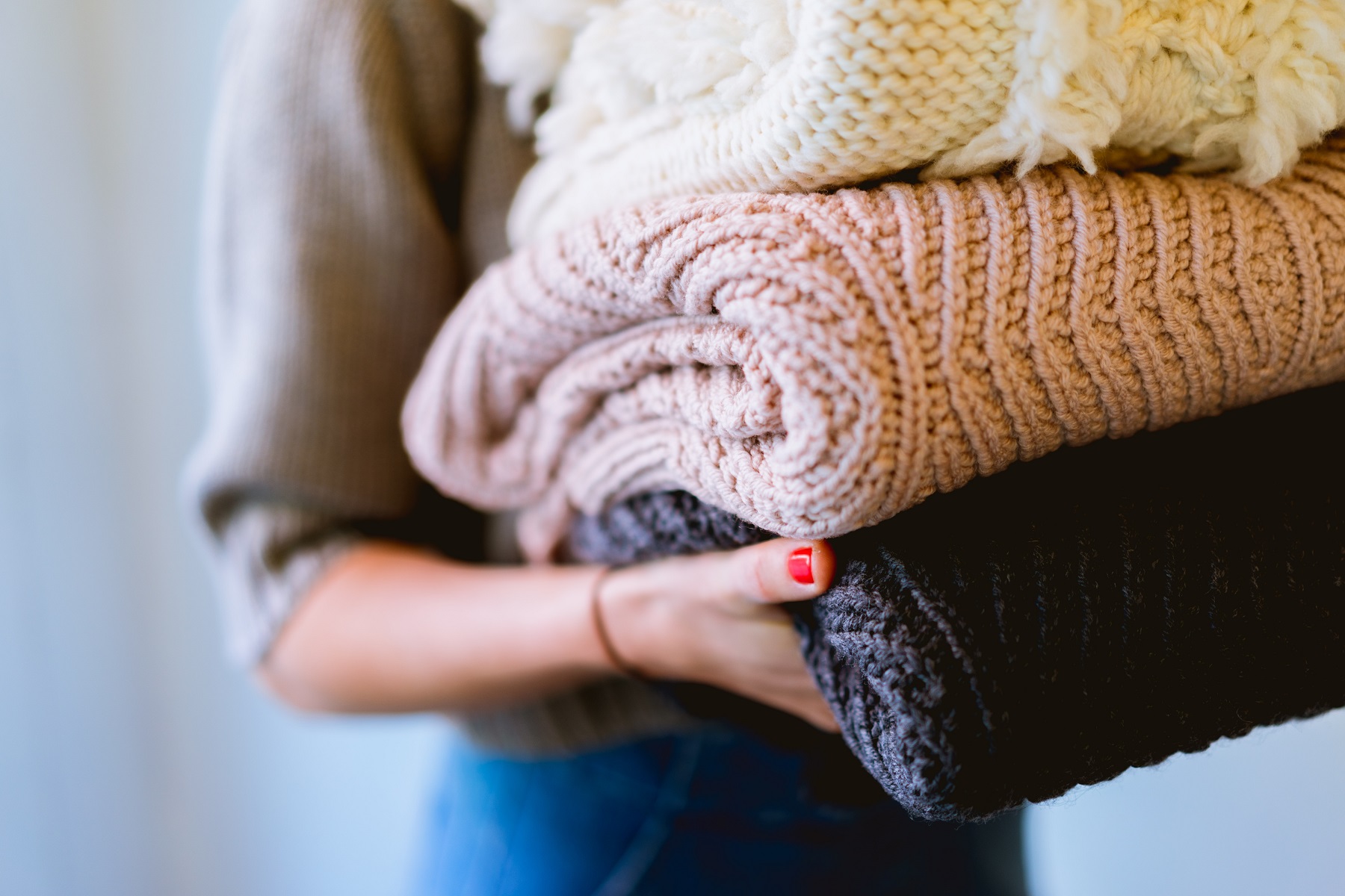Ein Mädchen trägt drei Strickpullover, ihr Gesicht ist nicht zu sehen. 