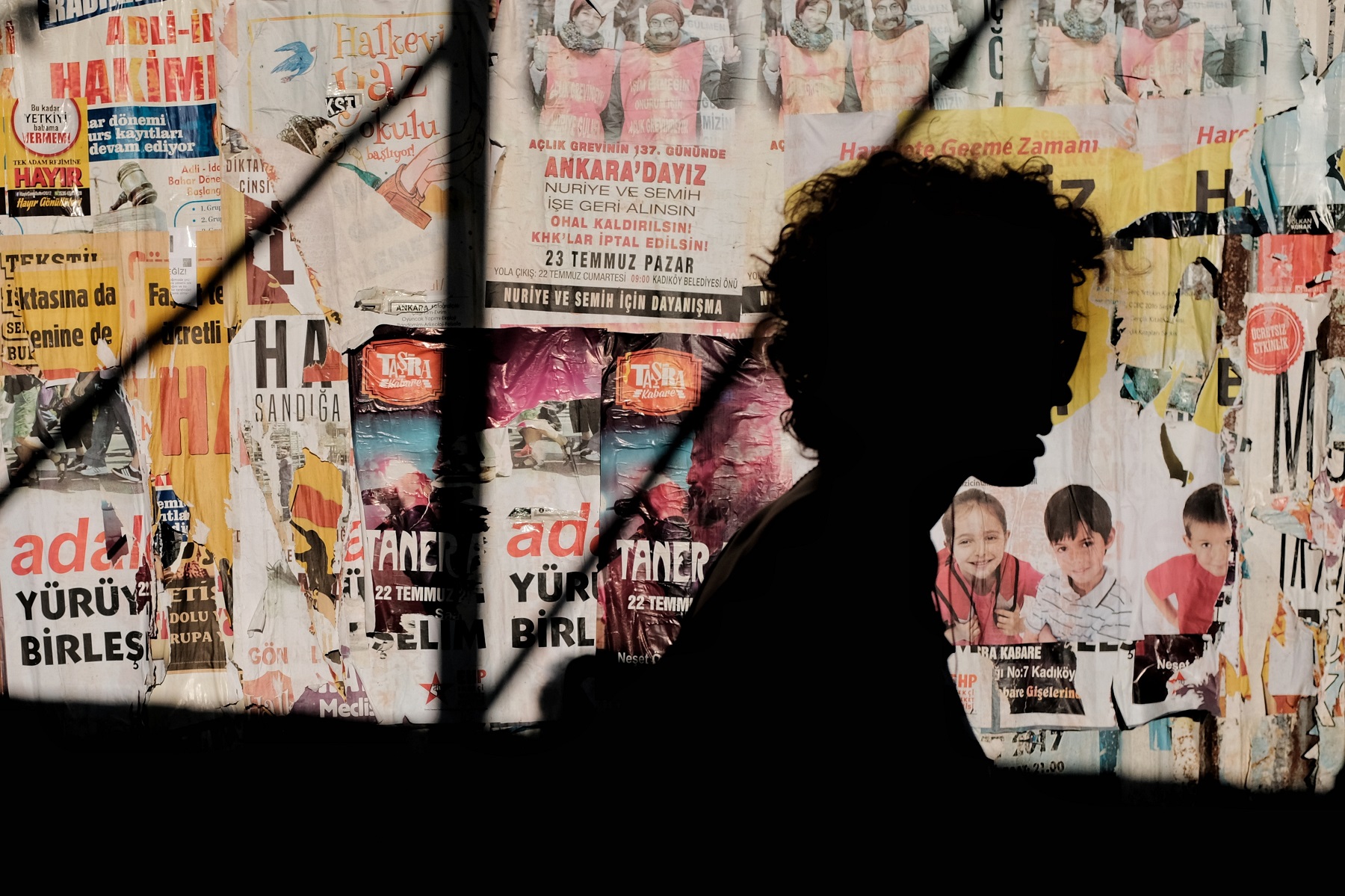 Silhouette einer Person vor einer Wand mit Zeitungs- und Newsartikeln