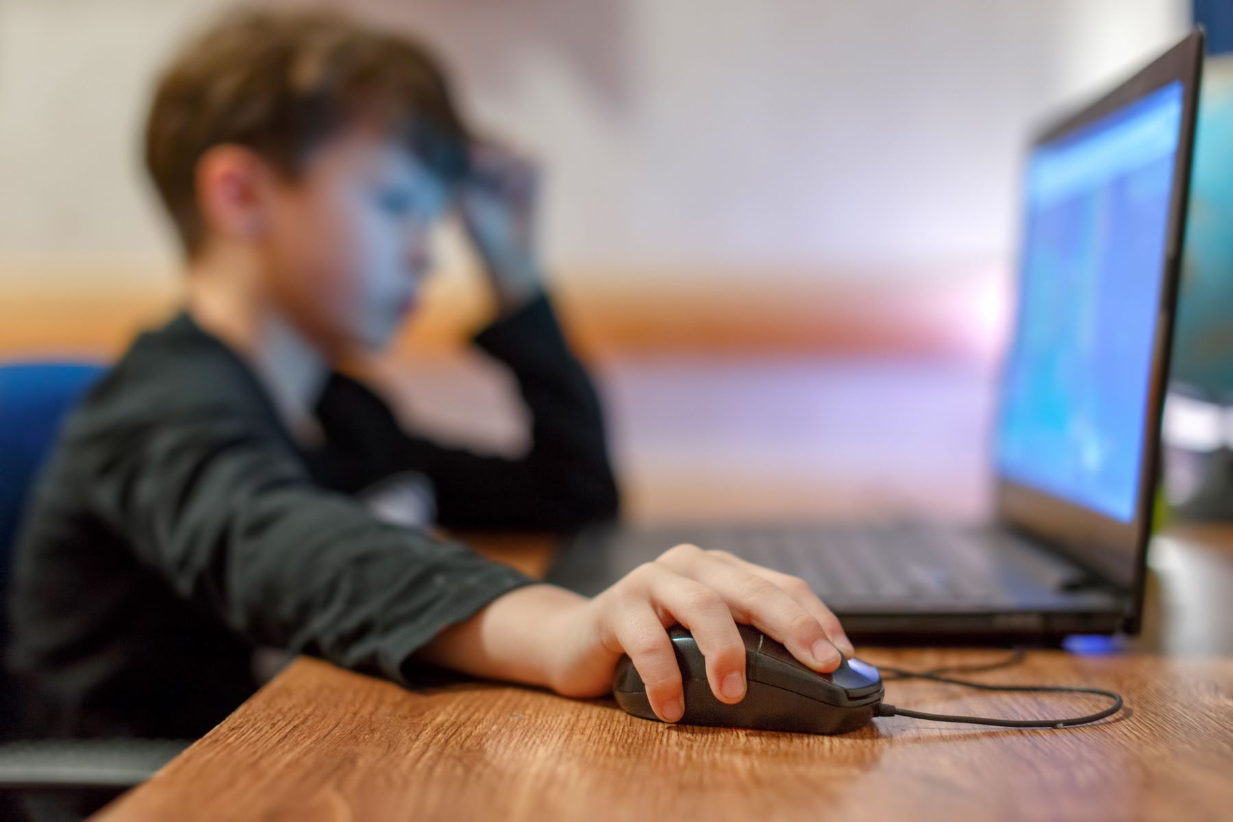 Braunhaariger Junge sitzt seitlich vor einem Computer-Bildschrim