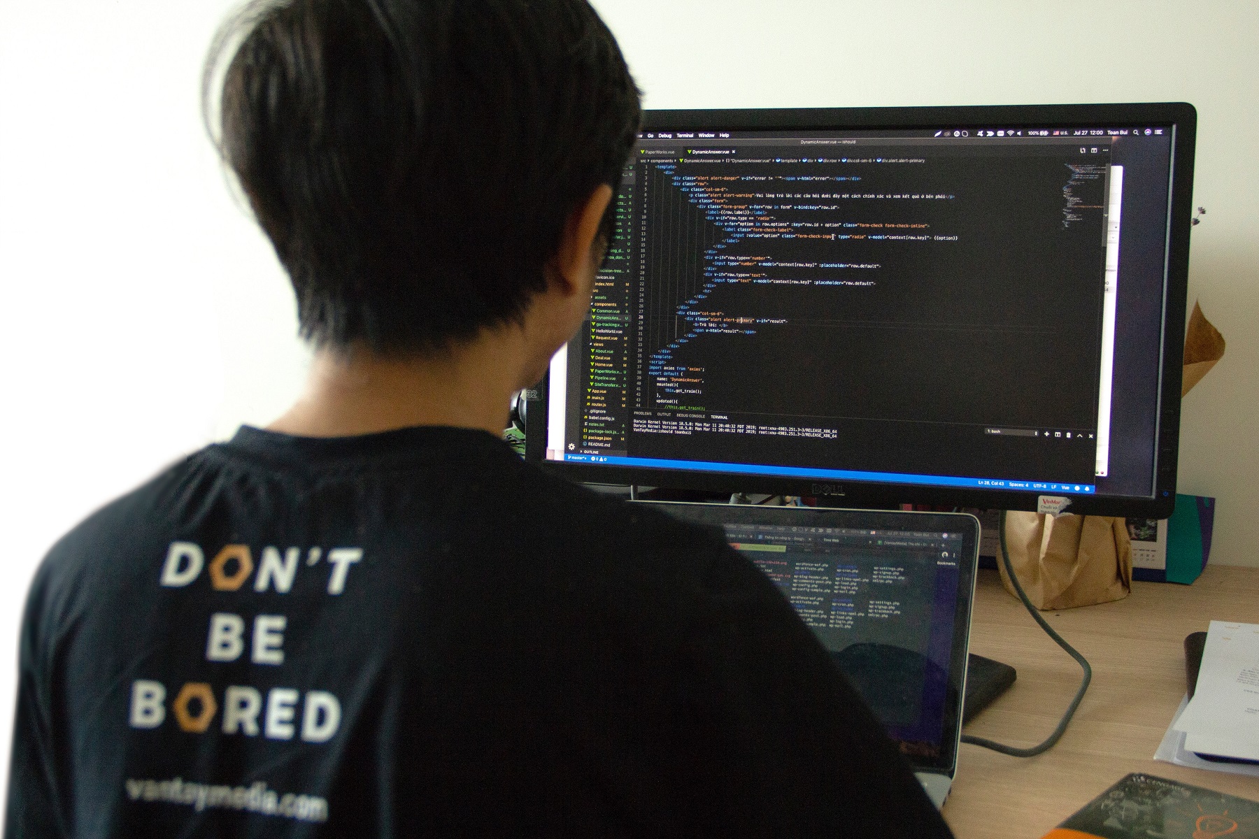 Kind sitzt mit dem Rücken zur Kamera und schaut auf einen PC auf dem Programmier-Codes zu sehen sind