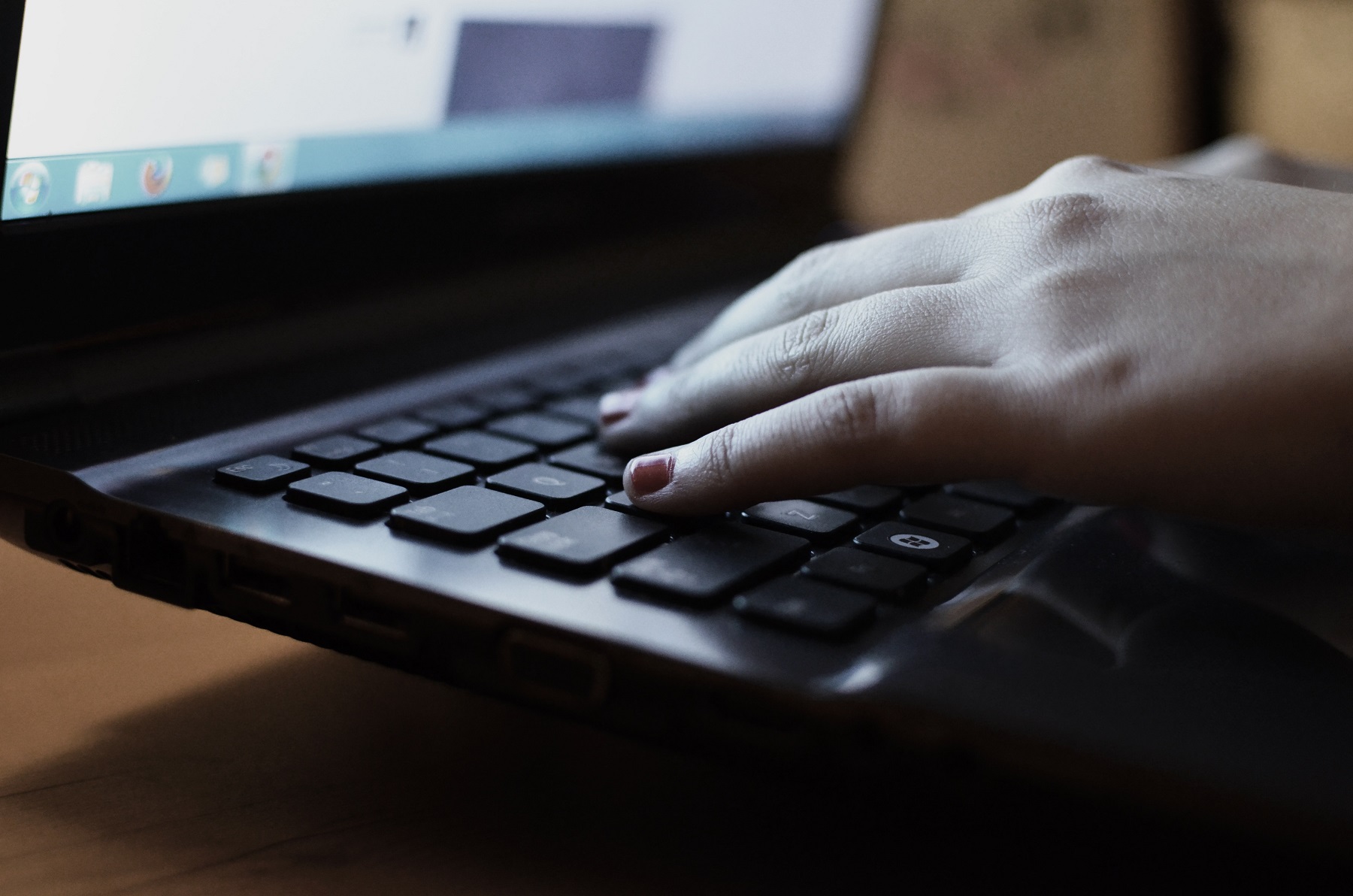 Eine Hand mit lackierten Fingernägeln tippt etwas auf dem Windows-Laptop