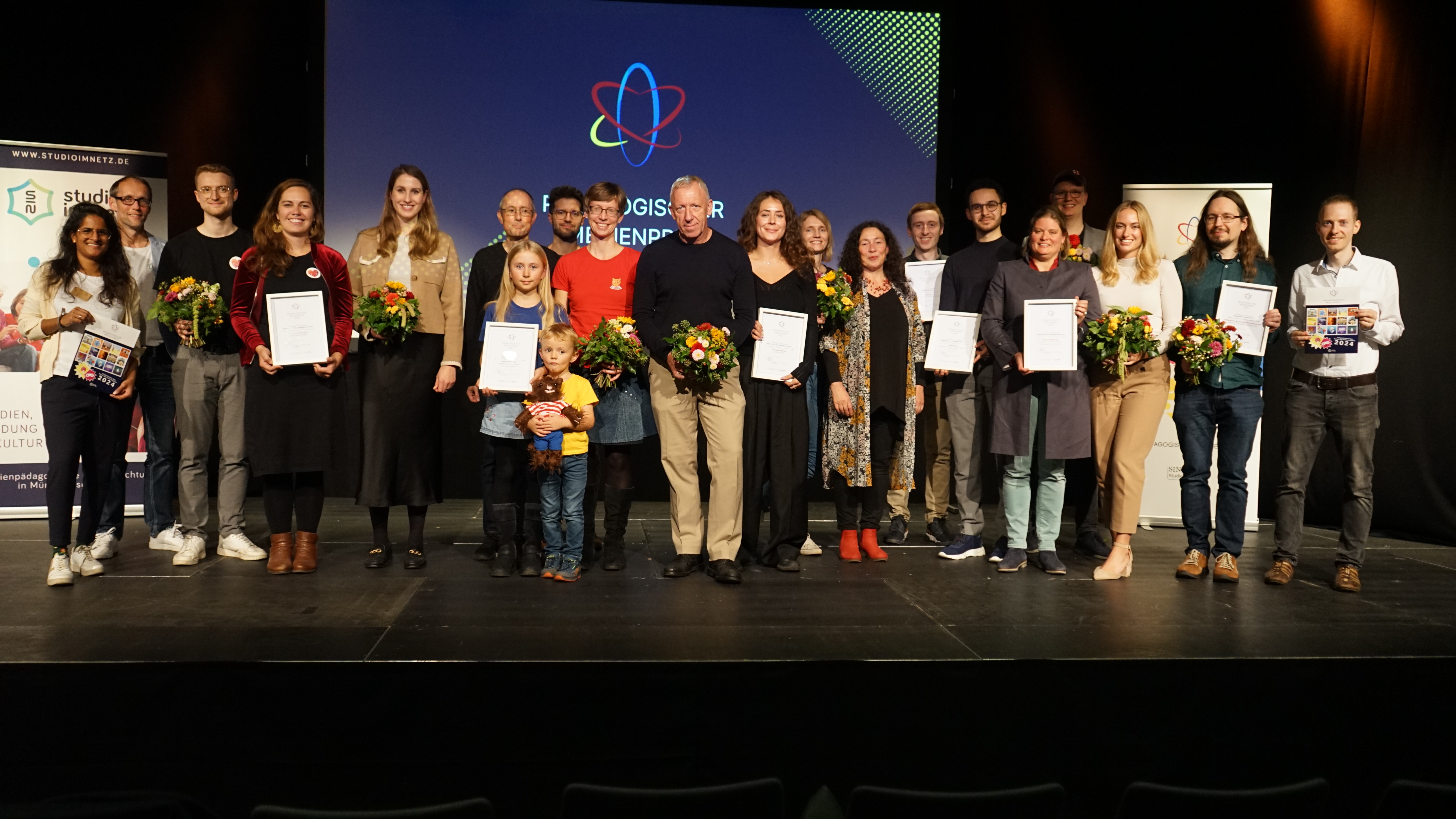 Gruppenfoto auf der Bühne mit allen Gewinner*innen des Pädagogischen Medienpreises 2024