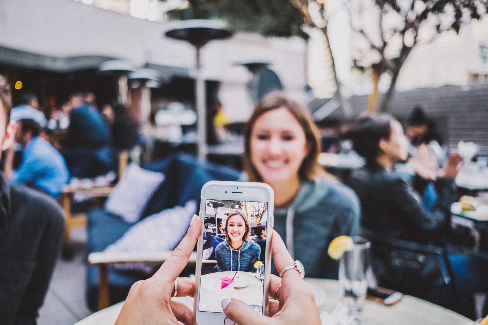 Jemand macht ein Foto einer jungen Frau mit dem Smartphone