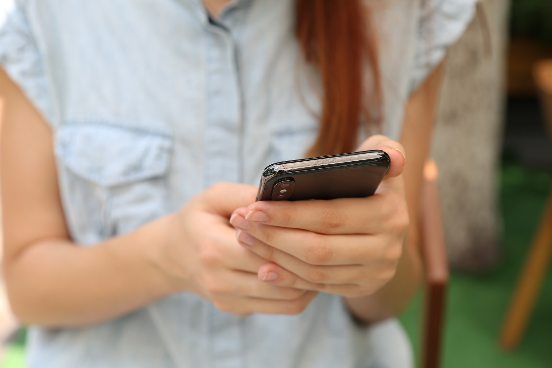 Eine junge Frau hält ein Smartphone in den Händen
