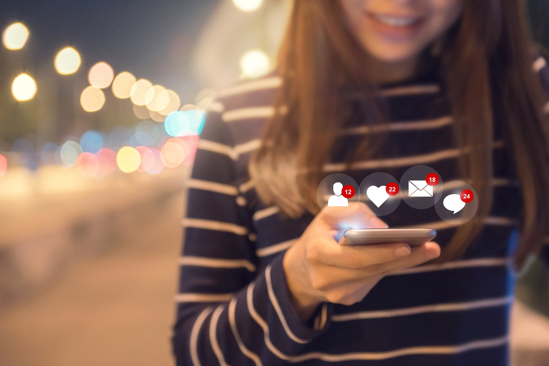 Eine Junge Frau hält ein Smartphone mit Hinweisen für neue Nachrichten