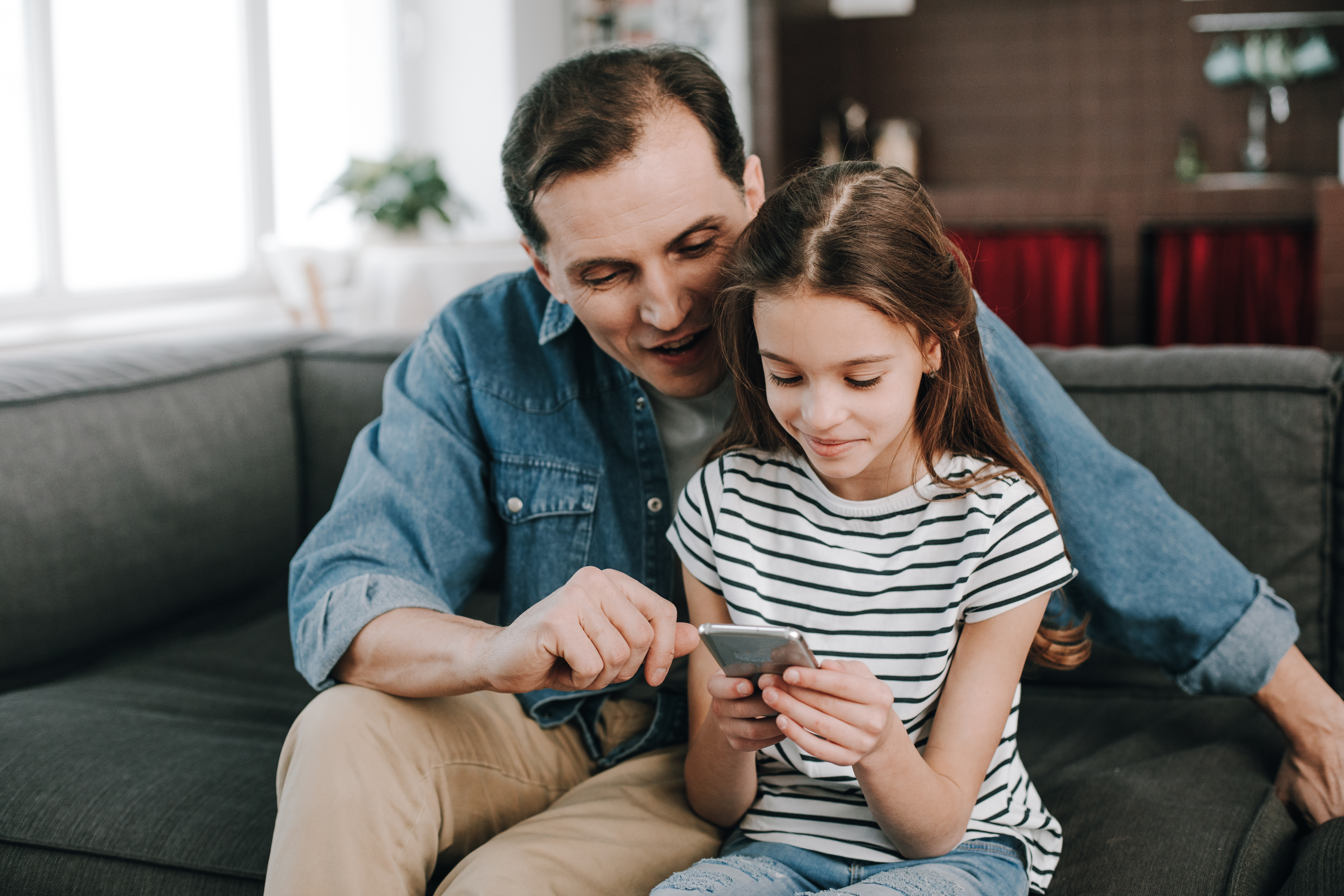 Vater und Tochter schauen gemeinsam auf ein Smartphone