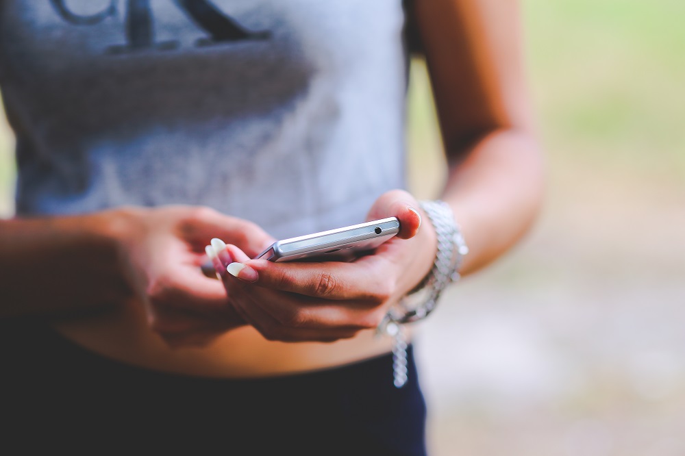 Eine Frau mit langen Fingernaegeln haelt ein Smartphone