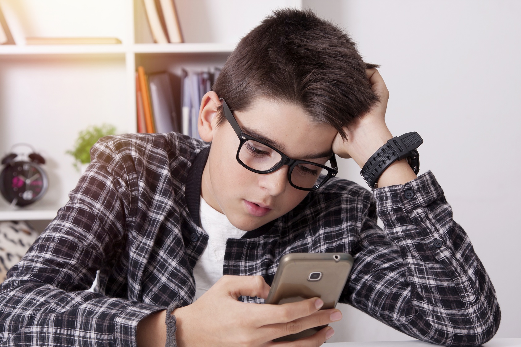 Ein Junge guckt gelangweilt auf ein Smartphone