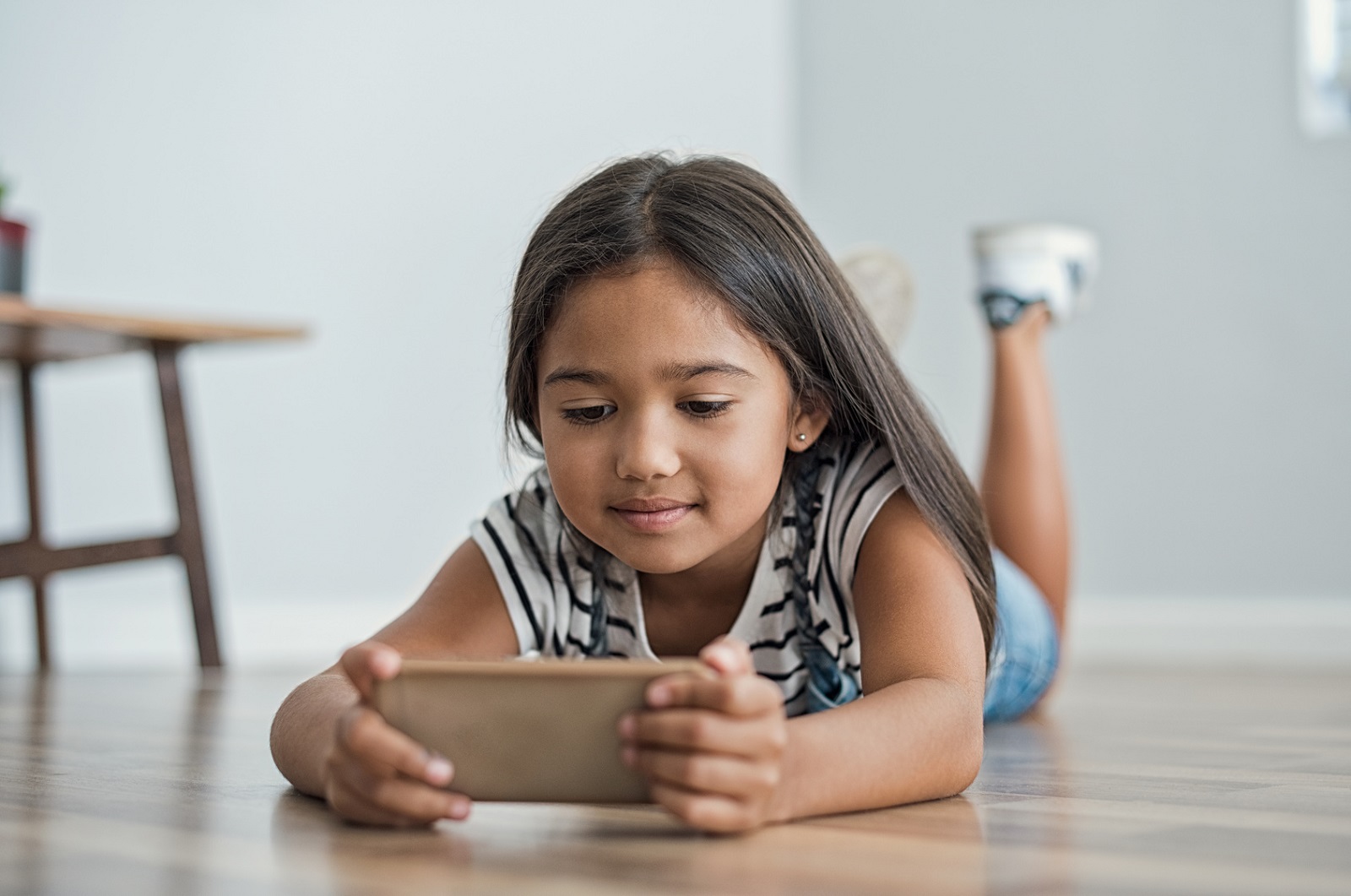 Ein Maedchen guckt im liegen auf ihr Smartphone