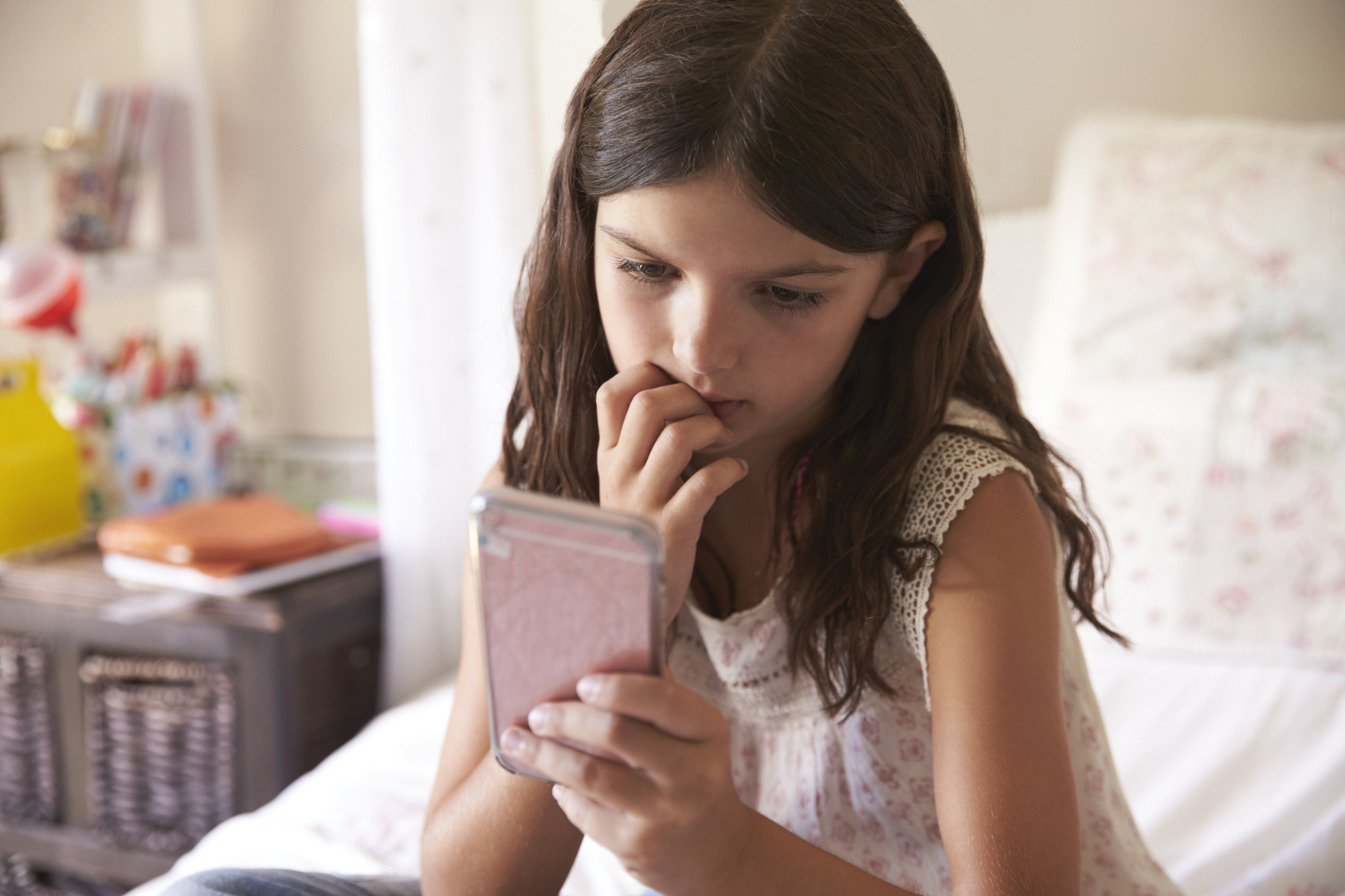 Ein Maedchen guckt gespannt auf ihr Smartphone