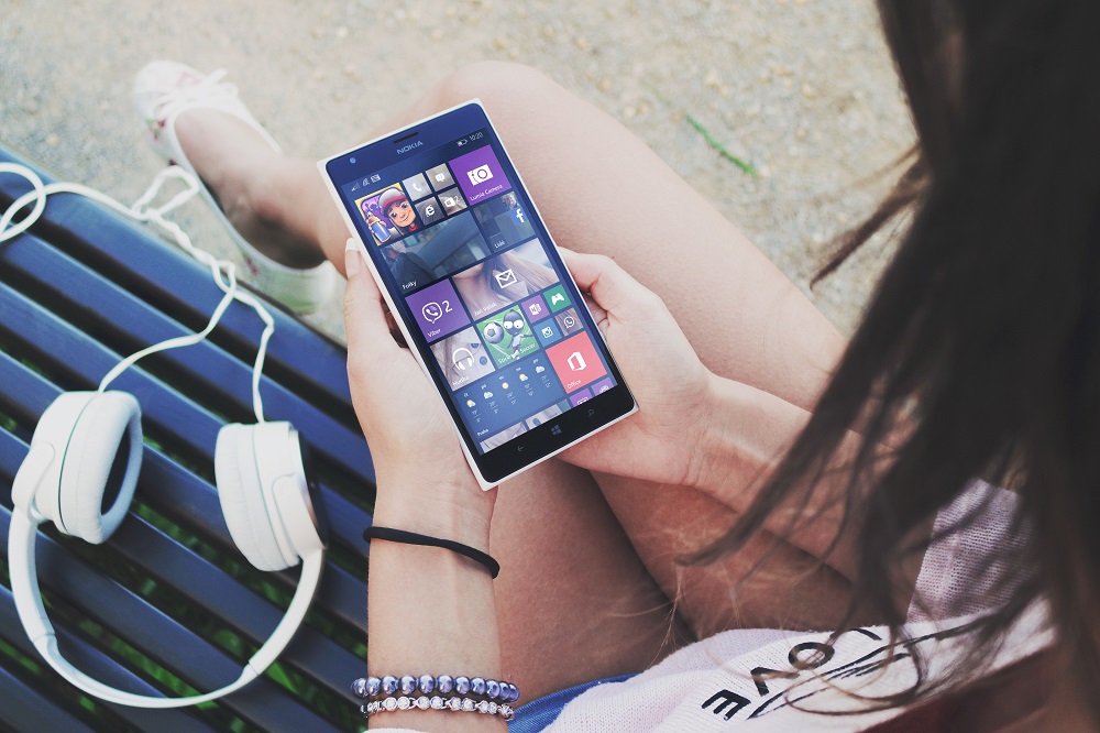 Ein jugendliches Maedchen haelt ein Nokia Smartphone