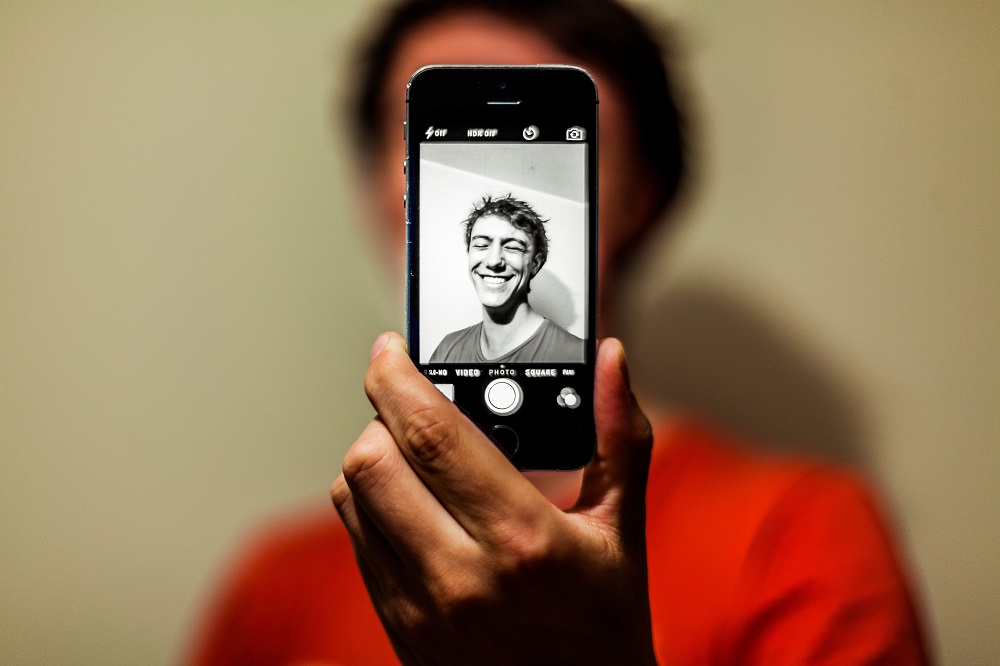 Ein junger Mann macht mit seinem Smartphone ein Selfie