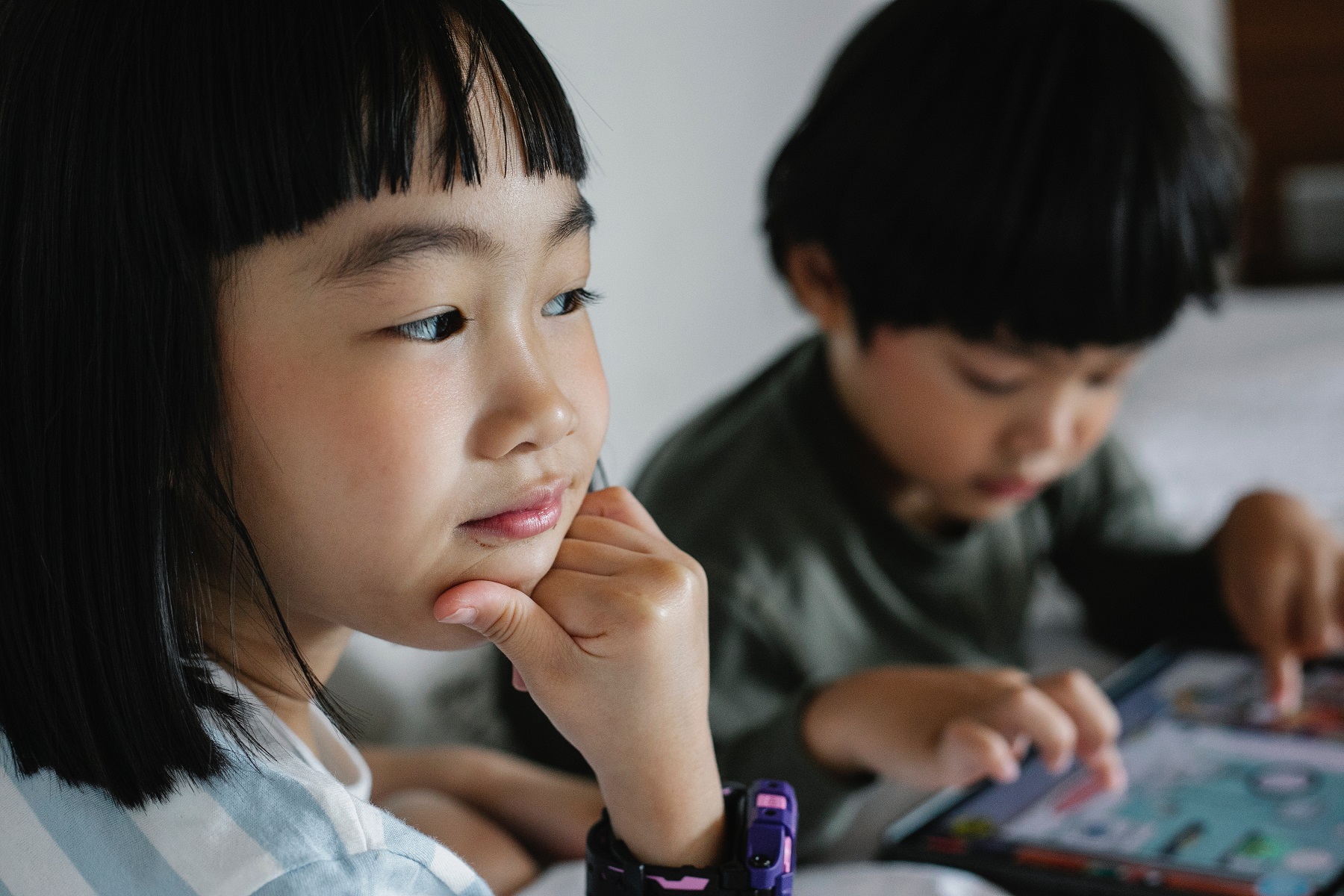 Ein Mädchen beobachtet ihren Bruder dabei, wie er ein Spiel auf einem Tablet spielt