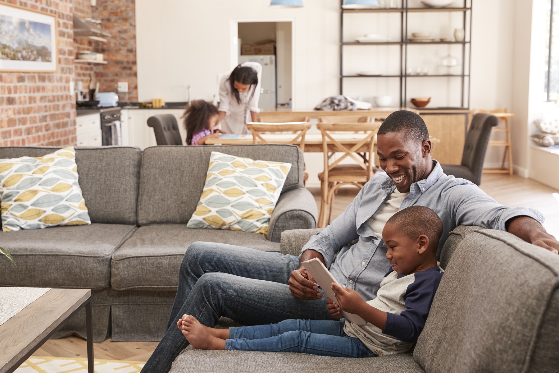 Vater und Sohn sitzen mit einem Tablet auf der Couch 