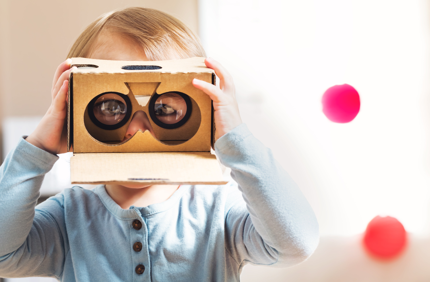Ein Kind trägt ein VR-Brillengestell aus Pappe